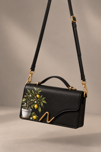 Load image into Gallery viewer, Signature N Lemon Tree black leather handbag hanging from its crossbody strap
